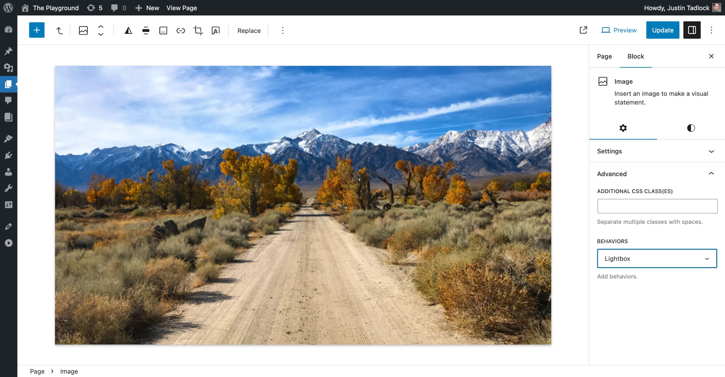 WordPress 文章编辑器，有一张通向山脉的土路图片。在块侧边栏中，Lightbox 功能在行为控件下被选中。